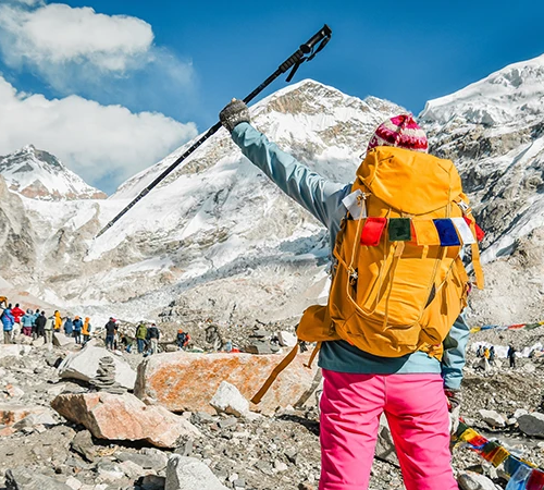 Everest Base Camp Luxury Lodge Trek traveler hiking toward base camp with snow-covered Himalayan peaks and prayer flags.