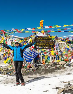 A line of trekkers crossing a high-altitude mountain pass decorated with thousands of colorful Buddhist prayer flags during an Annapurna Circuit Trek.