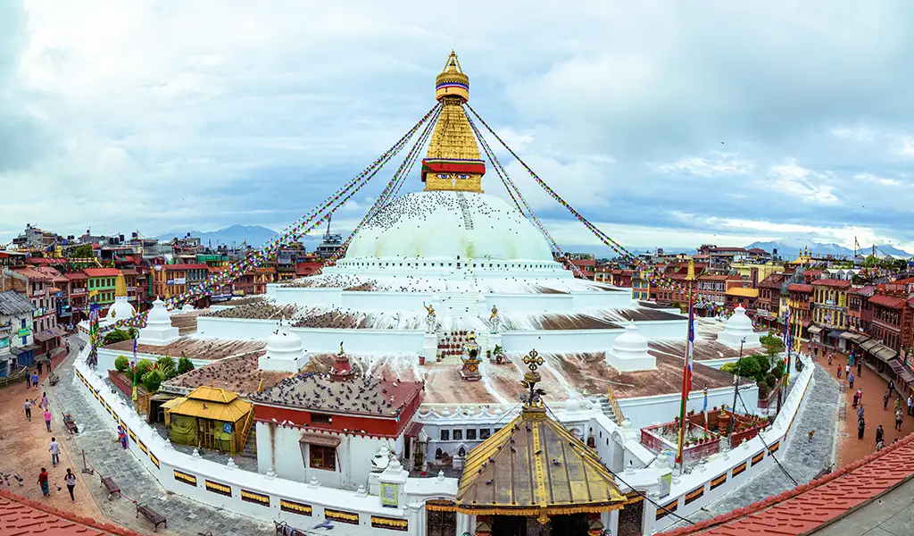Boudhanath Stupa in Kathmandu with prayer flags, monks, and surrounding streets showcasing Nepal’s spiritual and cultural heart visited in the start of Annapurna Base Camp Trek for beginners trip.