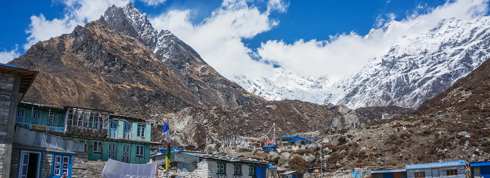 A view of Langtang Valley in Nepal showing a stone trail marker, a mountainous landscape, and clear sky.