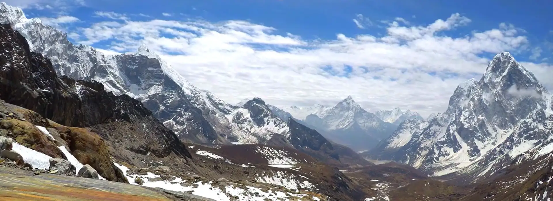 A wide panorama of the Himalayan range showing rugged valleys and snowy summits under a bright blue sky, ideal for those interested in Lobuche Peak climbing.