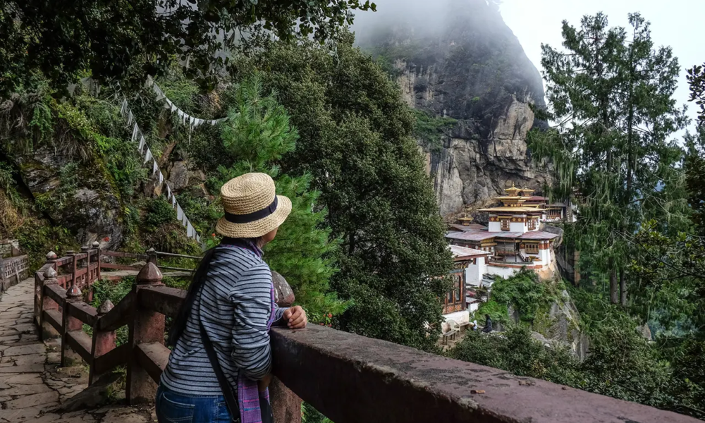 Visitor overlooking Tiger’s Nest Monastery on a misty cliff in Paro, Bhutan.