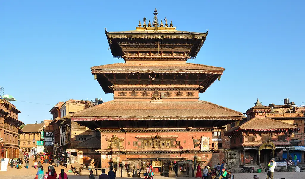 A large multi-tiered pagoda-style temple stands in a busy historic square with people walking around it.