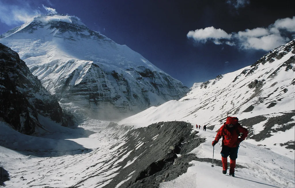 Trekkers ascending French Pass with the towering peak of Mount Dhaulagiri in the background.