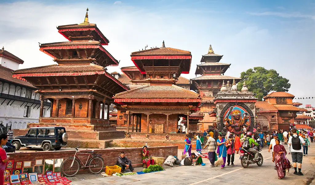 Kathmandu Durbar Square in Nepal with traditional Newari temples, local vendors, and visitors walking through the historic courtyard.