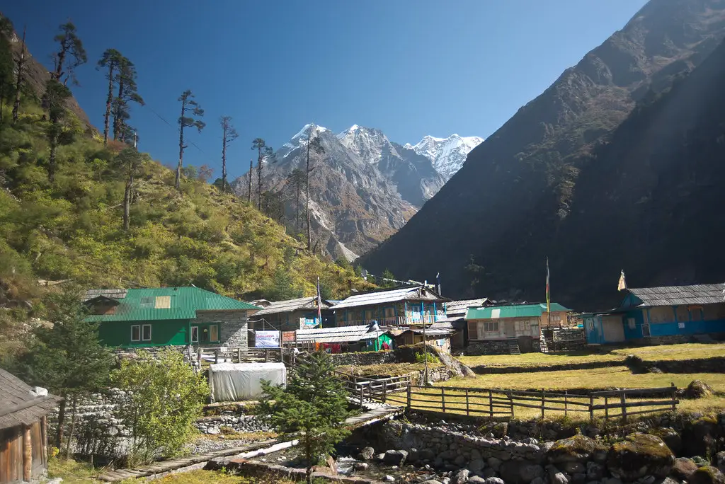 Traditional teahouses in Kothe village with snow-capped Himalayan peaks in the background along the Mera Peak route.