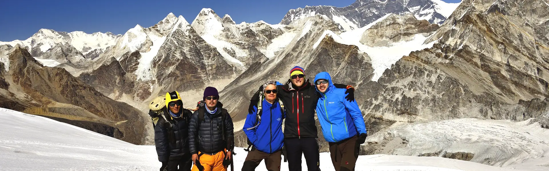 Group of climbers standing on the snowy slope of Mera Peak with the towering Himalayan mountains in the background.