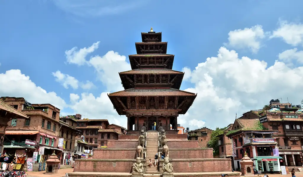 A tall five-tiered pagoda-style temple rises above a brick square, with traditional buildings on either side.