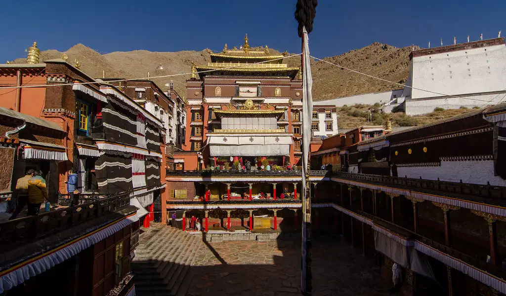 Tashilhunpo Monastery courtyard with traditional Tibetan architecture and golden-roofed main temple under a clear blue sky in Shigatse, Tibet.