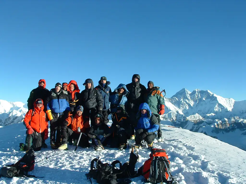 Group of climbers posing at the summit of Mera Peak with Everest and Lhotse in the background.Title: Climbers Celebrating at Mera Peak Summit