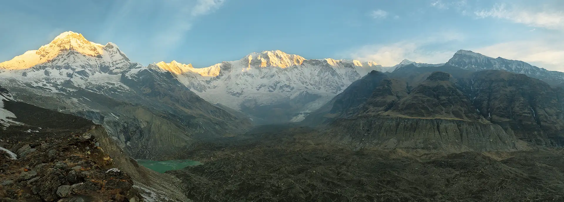 Snow-covered Annapurna mountain range glowing in early morning light above a deep Himalayan valley, illustrating annapurna circuit trek height and high-altitude terrain.