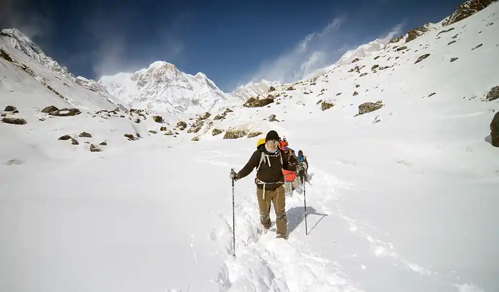 Trekkers moving through deep snow on a high-altitude Annapurna trail, showing annapurna circuit trek height and annapurna base camp fitness demands.