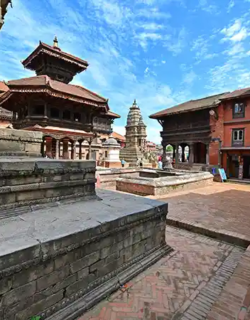 Stone temples and brick buildings line a historic square with pagoda-style structures under a blue sky.