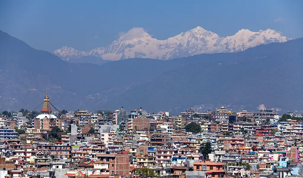 Kathmandu Valley cityscape with Boudhanath Stupa and snow-capped Himalayan mountains in the background, Nepal.
