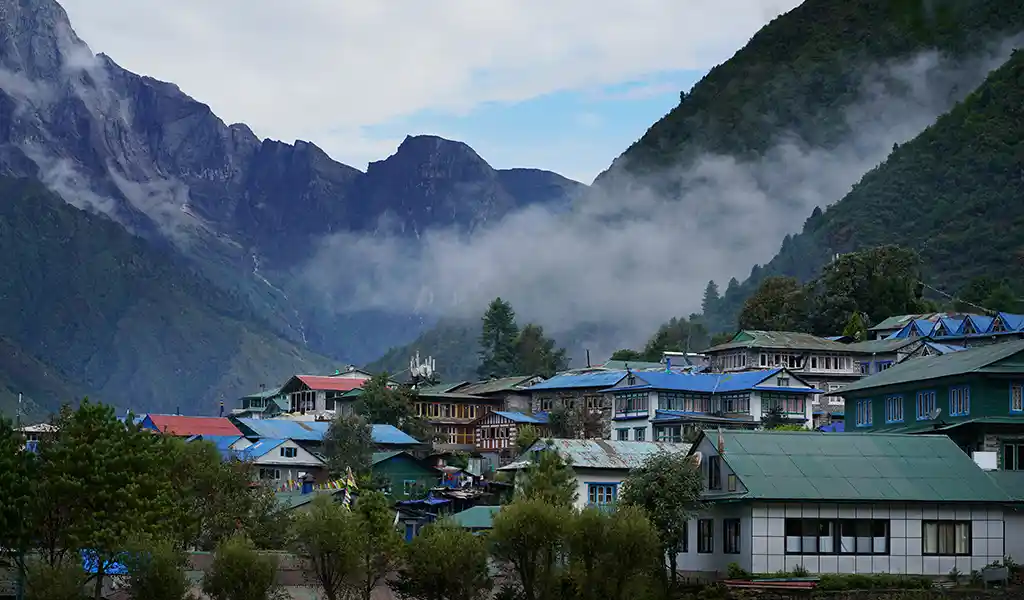 Lukla village with colorful rooftops nestled beneath steep Himalayan mountains and drifting clouds in the Everest region.