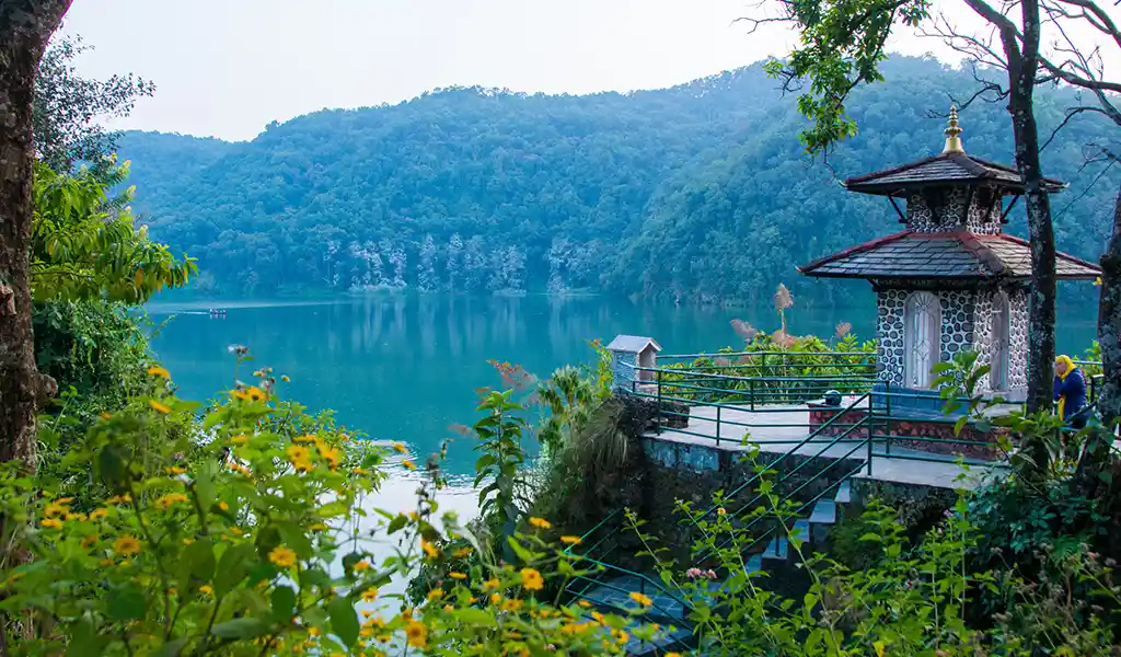 Peaceful lakeside pavilion near Phewa Lake in Pokhara, surrounded by lush green hills and calm turquoise water.