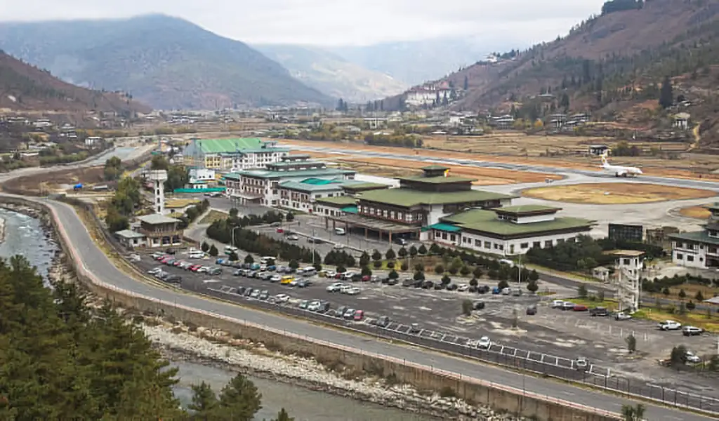 Paro International Airport in Bhutan surrounded by mountains, with the runway running through a narrow valley beside a river.