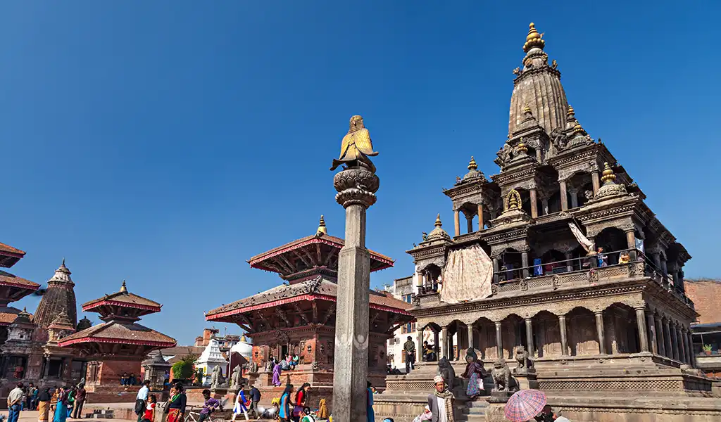 Patan Durbar Square in Lalitpur, Nepal, with historic temples, traditional architecture, and visitors walking in the courtyard.