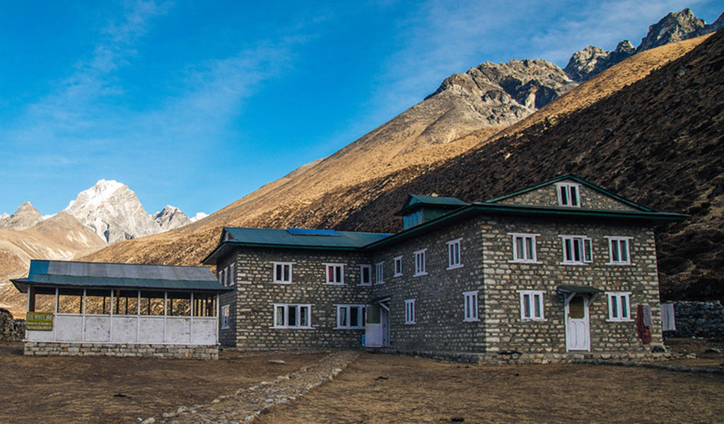 Stone lodges in Pheriche village set beneath barren Himalayan slopes and distant snow-capped peaks along the Everest Base Camp trek.