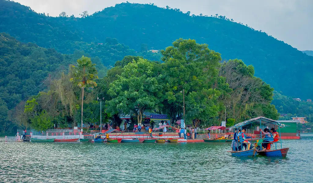 Boats on Phewa Lake in Pokhara with Tal Barahi Temple island and green hills in the background, Nepal.