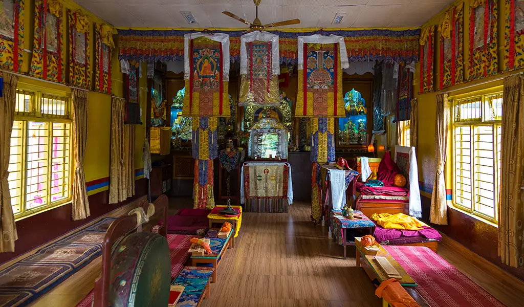 Interior of a Tibetan Buddhist prayer hall with colorful wall hangings, cushions, and religious objects in tibetan refugee camp pokhara
