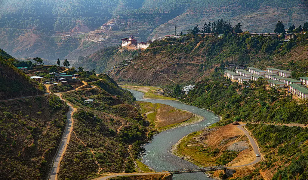 Wangdue Phodrang valley in Bhutan with a winding river, hillside roads, villages, and Wangdue Phodrang Dzong overlooking the landscape.