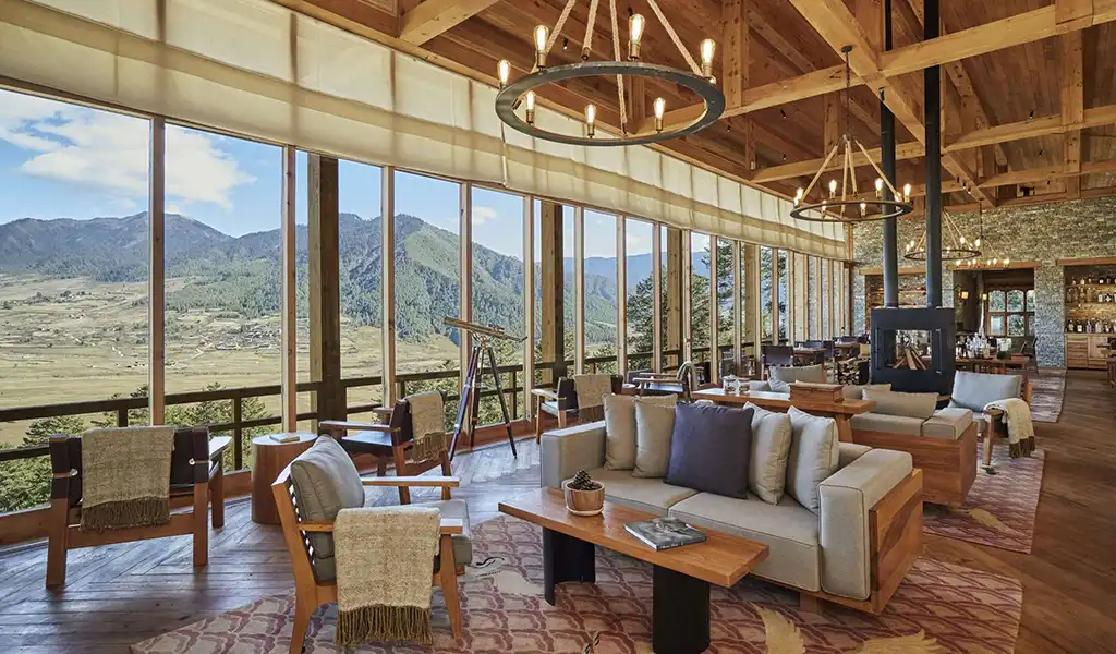 The elegant indoor lounge at Six Senses Bhutan, featuring large windows, wood accents, and a warm, modern aesthetic.