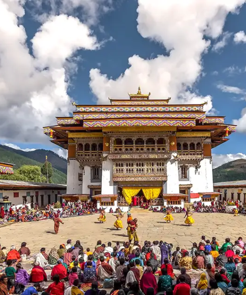 Bhutan festival at a traditional dzong courtyard with masked dancers and local crowd gathered.