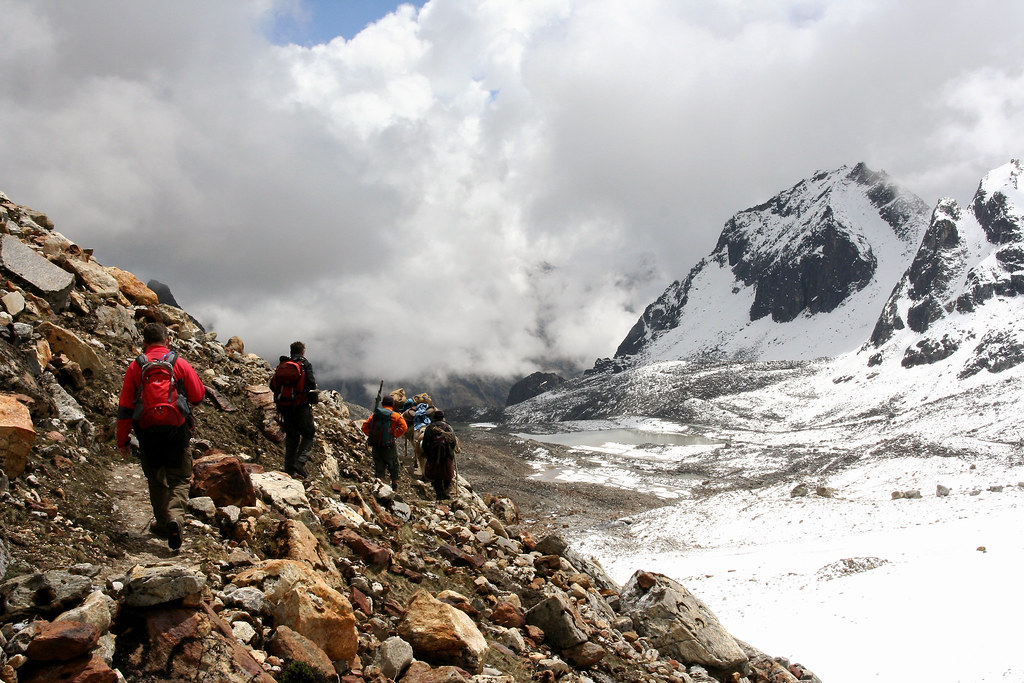 Trekkers crossing rocky glacier terrain during Snowman Trek Bhutan