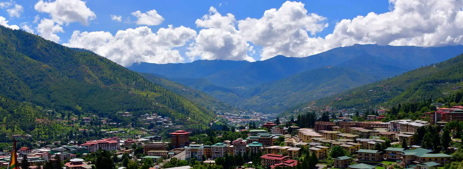 Panoramic view of Thimphu city surrounded by green Himalayan hills, featured in Bhutan travel FAQs.