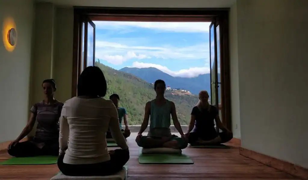 A group of people practicing outdoor meditation in a scenic valley during a Bhutan spiritual tour.
