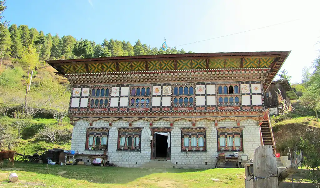 A traditional Bhutanese farmstay with white-washed walls and colorful wooden windows, perfect for Bhutan family travel.