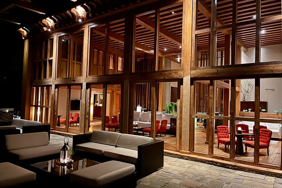 COMO Uma Punakha luxury lodge in Bhutan with glass façade and warm wooden interiors at night, ideal place mentioned in Bhutan accommodation guide.