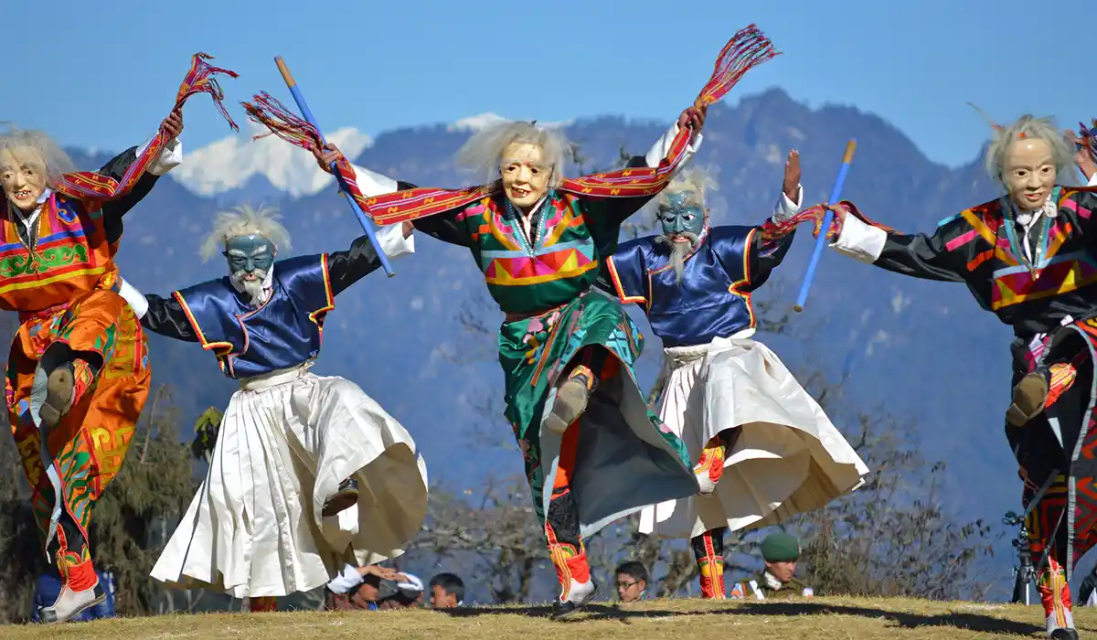 Masked dancers perform at Dochula Pass festival during Bhutan Off-Season Travel, wearing vibrant traditional costumes against mountain backdrop.