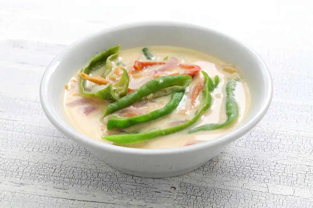 A close-up shot of a bowl of Ema Datshi, a spicy chili and cheese stew, being served as part of an authentic Bhutanese food