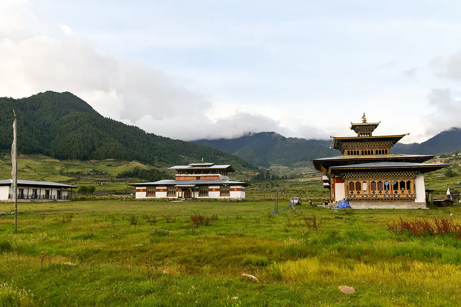 Khewang Lhakhang monastery surrounded by green meadows in Phobjikha Valley Bhutan with traditional Bhutanese architecture.