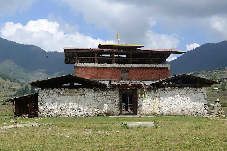 Kumbu Lhakhang monastery located in Phobjikha Valley Bhutan surrounded by open pastureland and Himalayan hills.