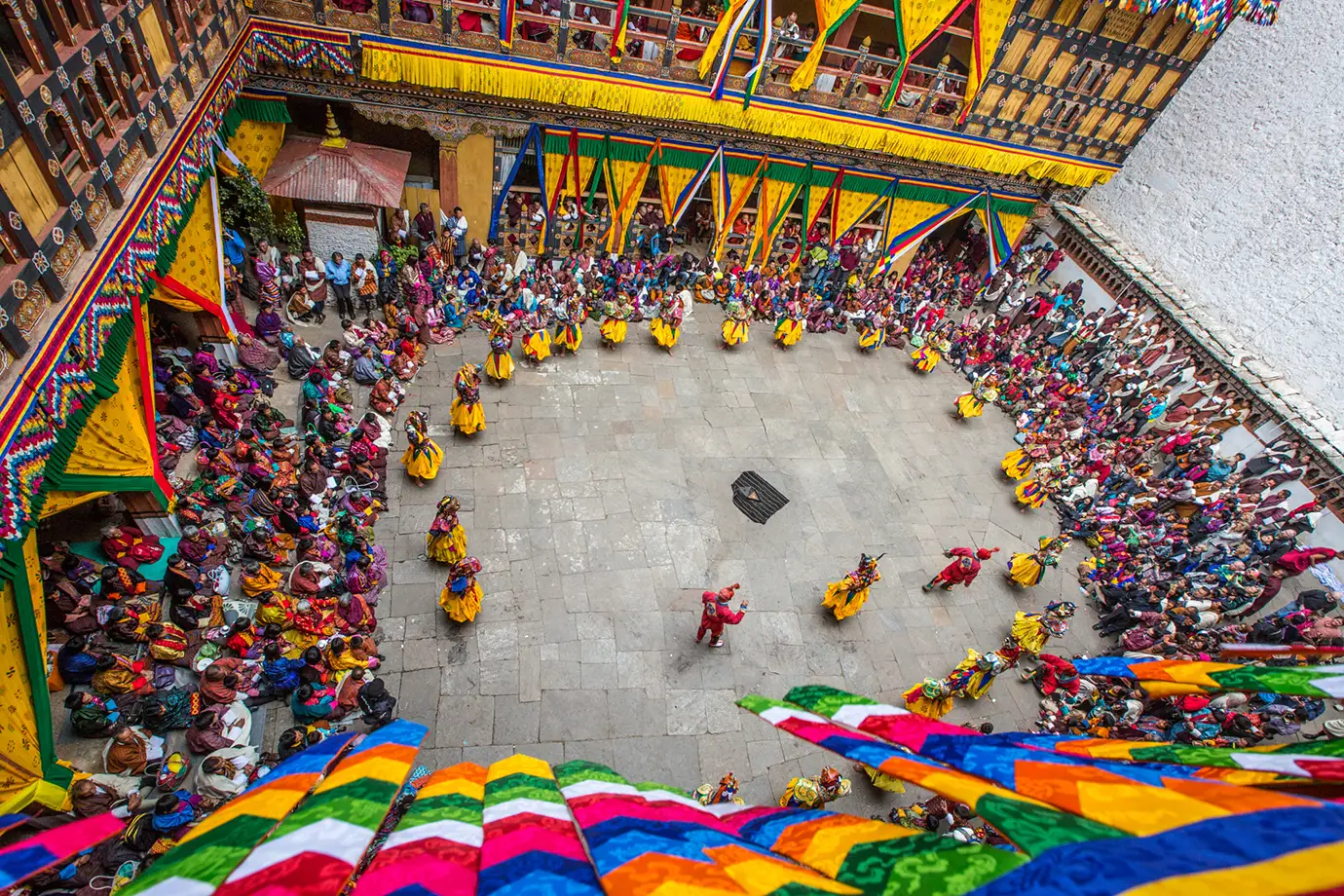Paro Tsechu Festival in Bhutan with masked dancers performing cham dance inside a dzong courtyard, a perfect time for Bhutan photography tour