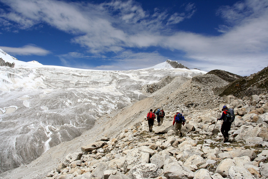 Trekkers walking on rocky trail during Snowman Trek Bhutan near snow-covered Himalayan peaks