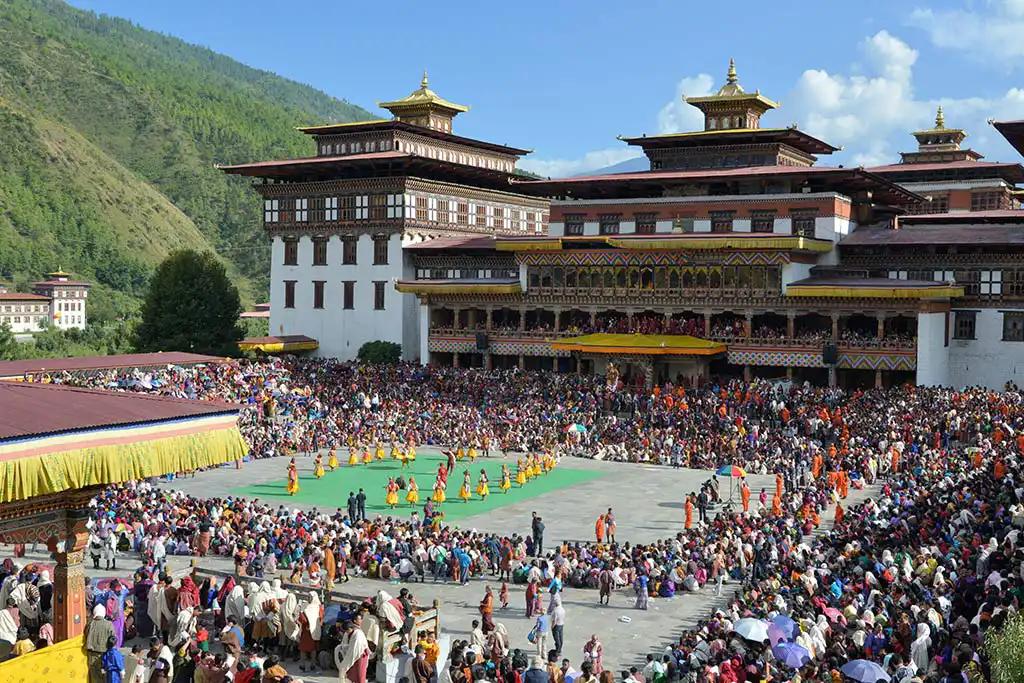 A colorful masked dancer in ornate robes performs a ritual Cham dance during a festival on a Bhutan spiritual tour.