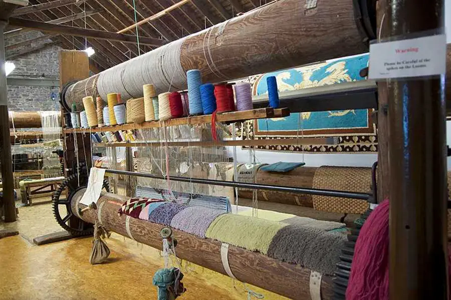 Traditional hand weaving process at Wangmo Hand-Woven Carpet Factory near Phobjikha Valley Bhutan showing colorful yarn and wooden loom.