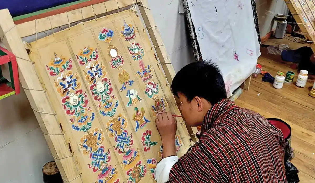 Bhutanese artisan painting traditional motifs at a Zorig Chusum workshop, preserving Bhutan's Culture and Traditions through sacred art.