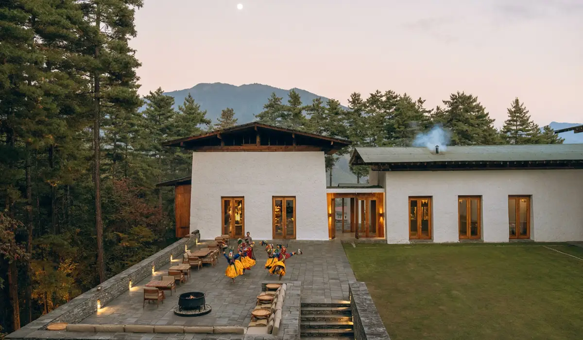 Luxury lodge in Thimphu with traditional dancers in the courtyard, featured in a comprehensive Bhutan accommodation guide amid serene pine forests and mountain views.