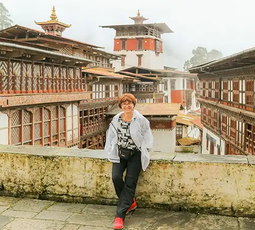 A close up shot of a traditional Bhutanese building with whitewashed walls, intricate red and gold woodwork, and ornate window frames. The best time to visit Bhutan to see these structures against clear skies is during the spring (March to May) or autumn (September to November).