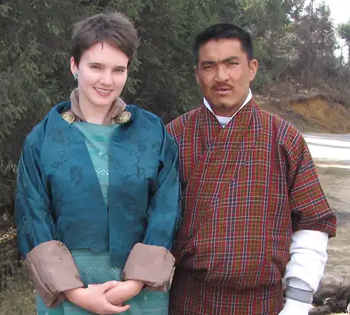 Two tourists posing in traditional Bhutanese attire, showing the cultural experiences included in the Bhutan travel cost.