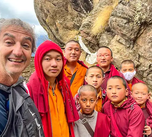 Senior traveler posing with young monks in Bhutan highlighting Bhutan travel for senior travelers