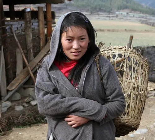 Local woman carrying a traditional basket in rural Bhutan reflecting authentic Bhutan village life.