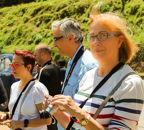 A group of diverse international tourists holding cameras and smartphones while exploring a scenic outdoor location, made possible by the efficient Bhutan Visa Process.
