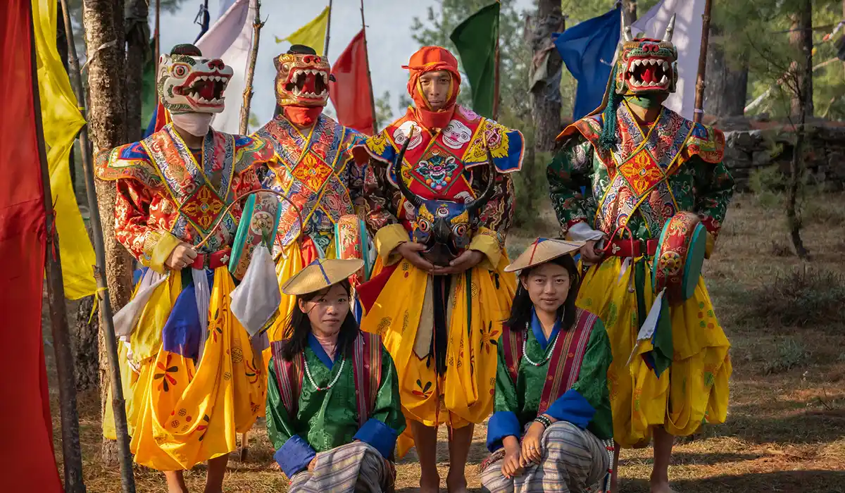 Bhutanese performers in colorful festival costumes and masks, representing Bhutan's Culture and Traditions during a sacred outdoor celebration.