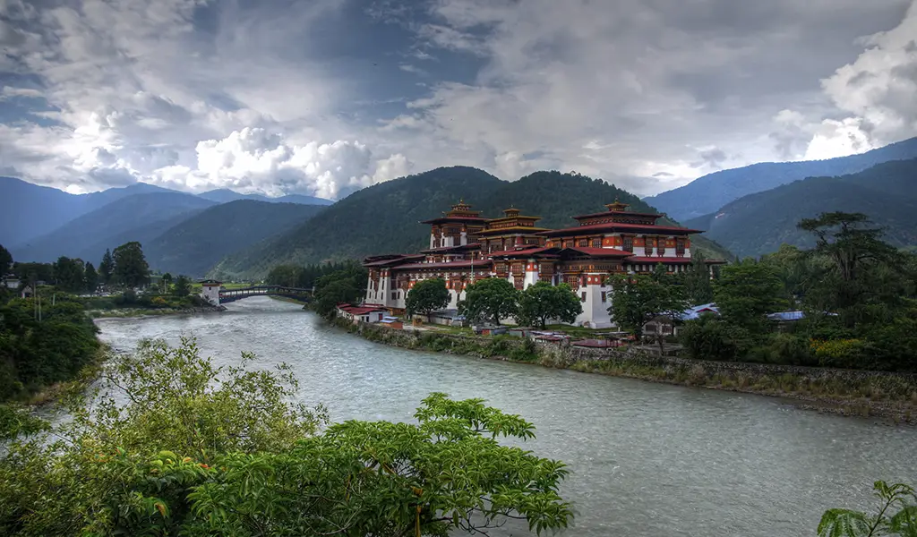 Punakha Dzong beside the Pho Chhu River surrounded by mountains, a scenic highlight during a Bhutan road trip.